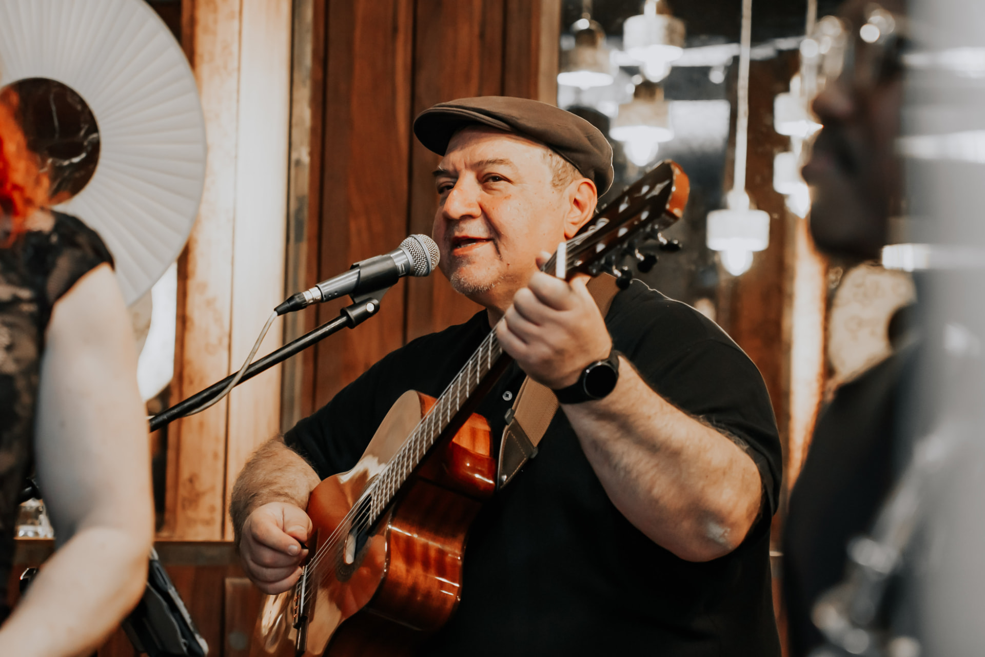 The guitarist singing into a microphone mid-song, hand raised off the strings.