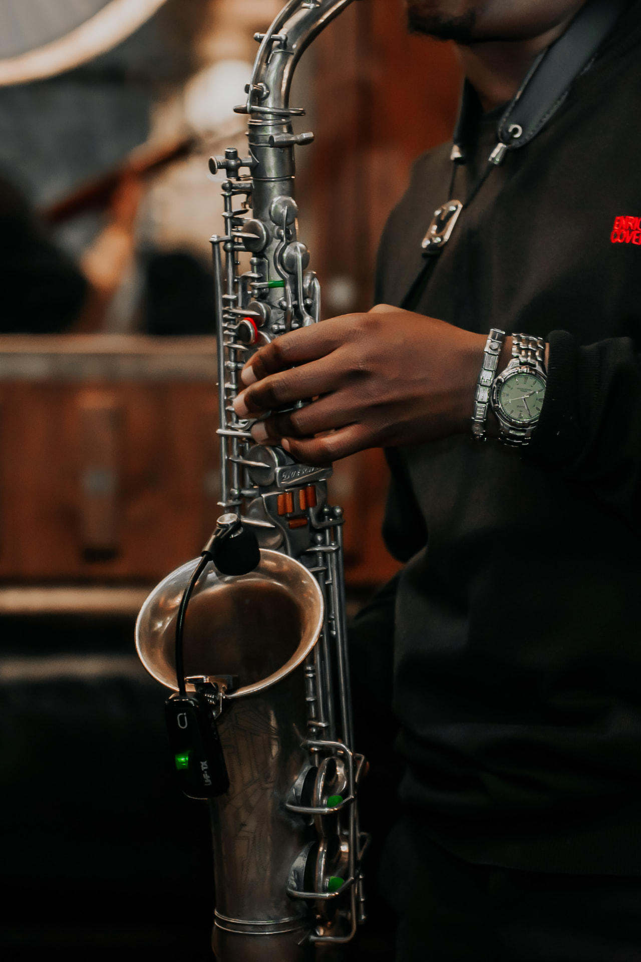 A saxophone held mid-phrase, wireless transmitter clipped to the bell.