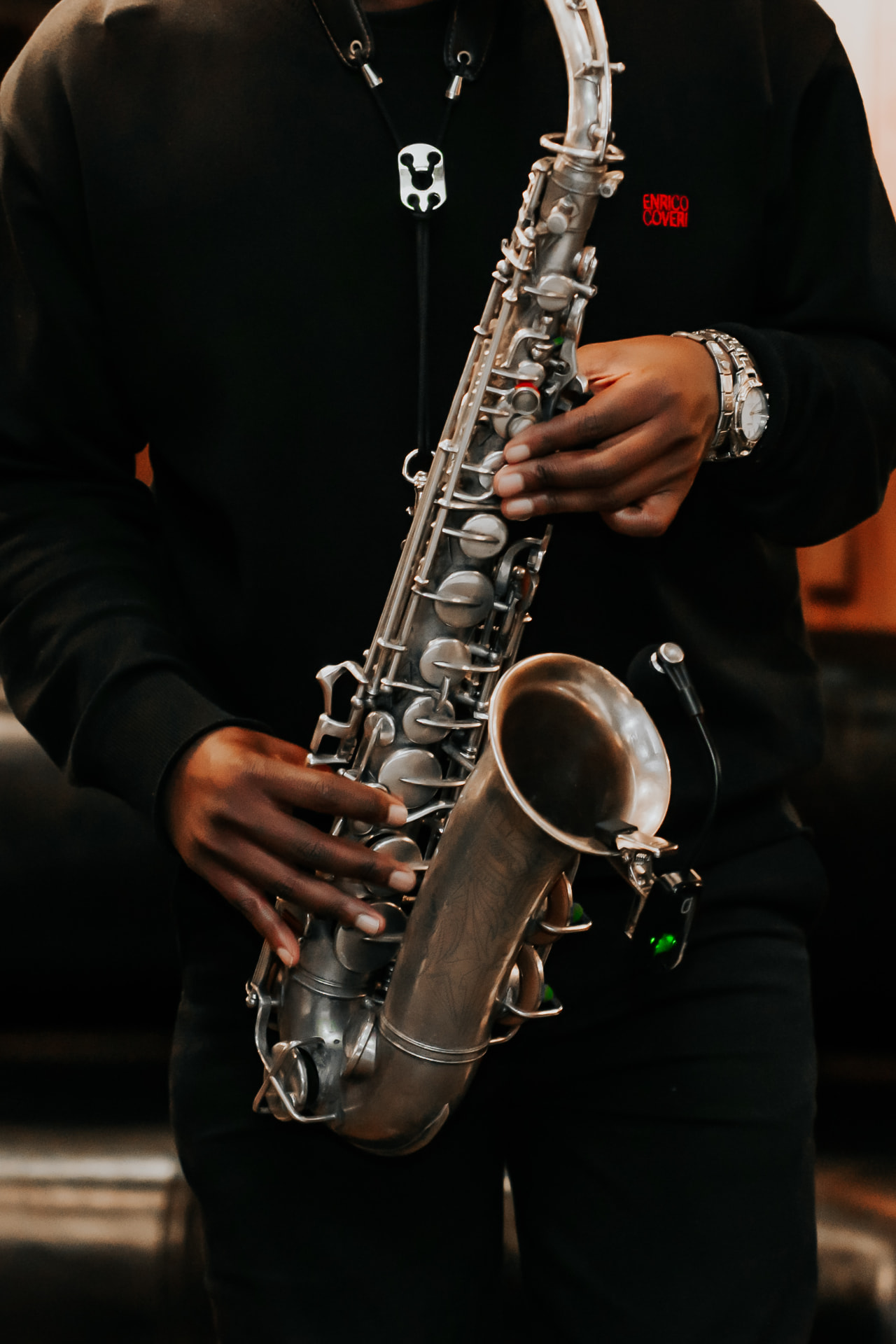 Close detail of hands on the keys of a silver saxophone.