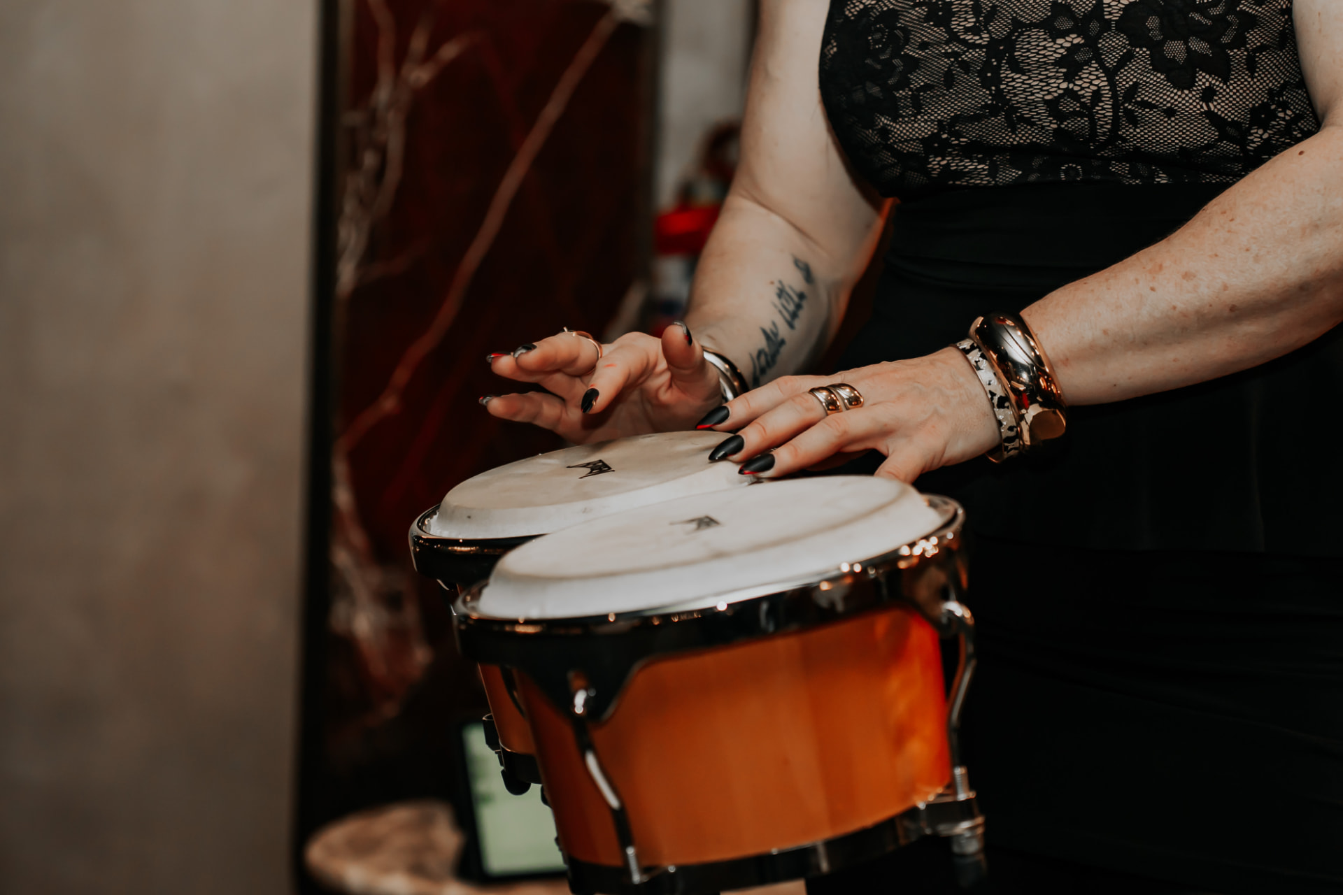 Hands mid-strike on bongo skins, rings and bangles catching the light.