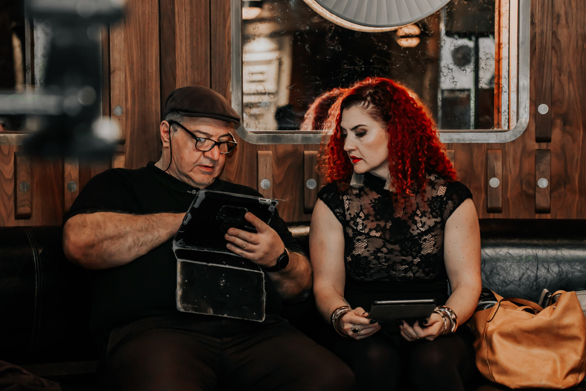 René Hunter and the guitarist sitting on a leather banquette between sets, reading from tablets.